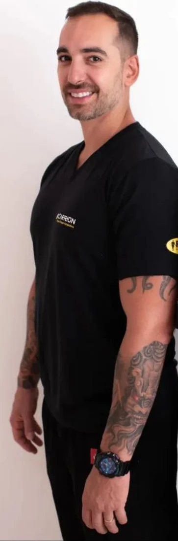 André Carrion de camiseta preta Carrion, sorrindo, com os braços tatuados
